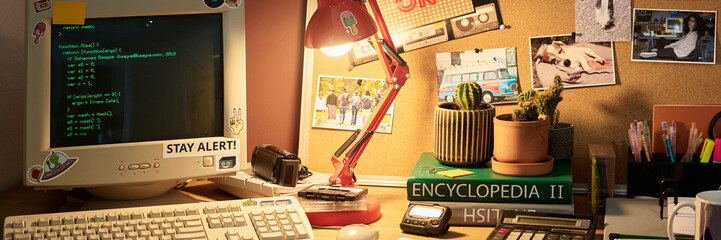Desk with retro computer and various decor items including plant pots, table lamp, and framed photos creating a personalized workspace