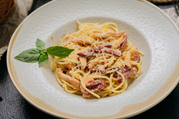 Classic carbonara pasta with Parmesan, basil, and crispy bacon strips, served in an elegant setting