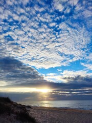 A stunning beach scene at sunrise with a dramatic sky filled with textured clouds