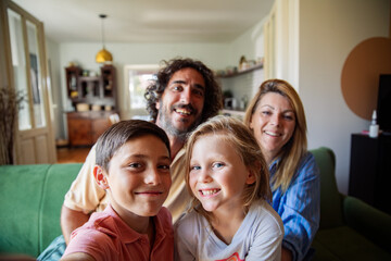Happy family taking group selfie on couch at home