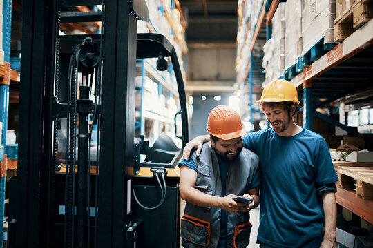 Warehouse workers with hard hats sharing a laugh on break