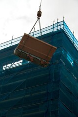 Large Concrete Debris on Crane Hook: Construction Site Scene with Scaffolding