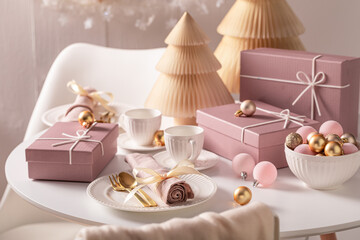 Modern table set for Christmas surrounded by baubles and decorations.