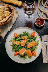 Gourmet arugula salad with smoked salmon and cherry tomatoes, served with red wine and rustic bread