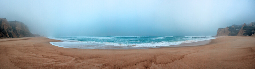 A wide, misty beach with gentle waves meeting the sandy shore, f