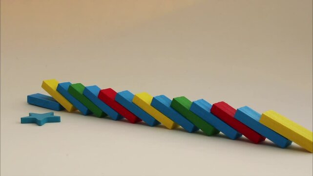 Colorful wooden pieces placed in a row fall one after another until they knock down the leader star