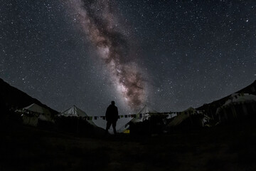Landscape with Milky Way. Night sky with stars and silhouette of a standing happy man on the mountain at chandrataal camp in spiti valley and lahaul himachal pradesh, India