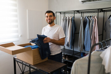 Latin man joyfully sorting and packing clothes in a walk-in closet during spring cleaning