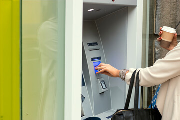 Attractive long haired brunette with shopping bags using automated teller machine