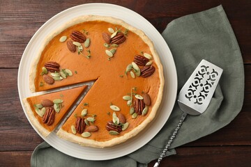 Tasty homemade pumpkin pie and server on wooden table, top view