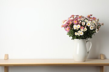 Vase with beautiful flowers on wooden shelf near white wall, space for text