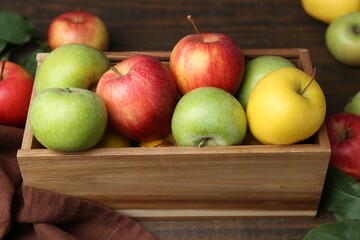 Fresh ripe apples in wooden crate on table, closeup