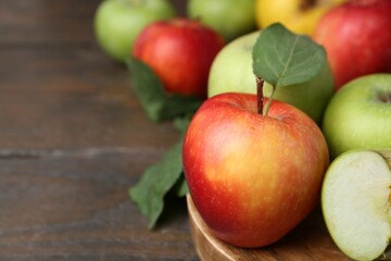 Different ripe apples on wooden table, closeup. Space for text