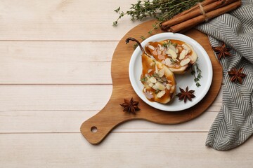 Delicious pears with caramel sauce, almond flakes and spices on white wooden table, flat lay. Space for text