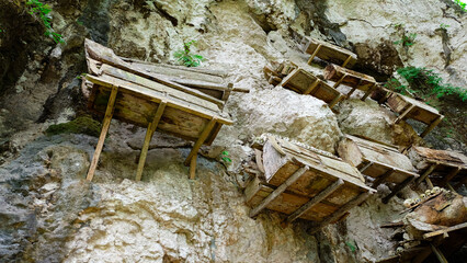 A cliff face in Indonesia with wooden coffins resting on ledges and in crevices. Toraja Burial Cliff