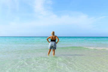 Cayo Coco,Cuba, young woman standing in tranquil,turquoise ocean,looking toward horizon line,sunny gorgeous day, vacation,travel background