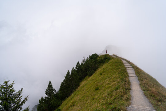 Misty mountain path in Stoos, Switzerland with lone hiker