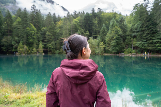Woman in maroon jacket overlooking serene Blausee Lake