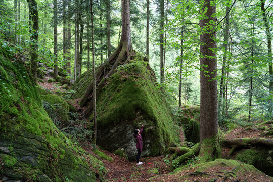 Woman Exploring Mossy Rock Formation in Naturpark Blausee, Switzerland
