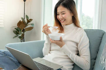 healthy food. Beautiful female girl enjoy eat yogurt, use laptop relax, fresh fruits on breakfast...