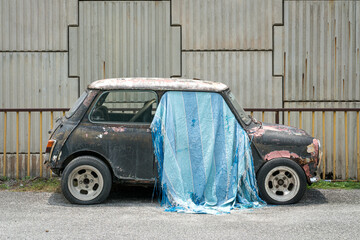 Abandoned Car with Blue Fabric Covering. Car paint oxidization and faded paint, abandoned by the road side.