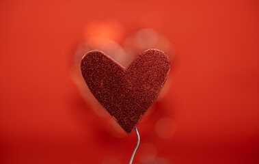 un corazón sostenido por alambre con fondo rojo desenfocado