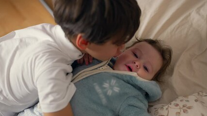 Young boy giving gentle kiss to baby on bed, showing affection and care, nurturing sibling moment, warm and intimate, family love and bonding, soft expression
