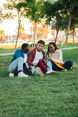 Vertical Three young students studying and doing homework on a university campus lawn, engaged in...