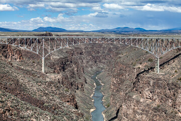 Fototapeta premium Rio Grande Gorge Bridge near Santa Fe, New Mexico, this steel arch bridge spans a deep canyon carved by the Rio Grande River, showcasing a stunning example of engineering amidst a rugged, high desert 