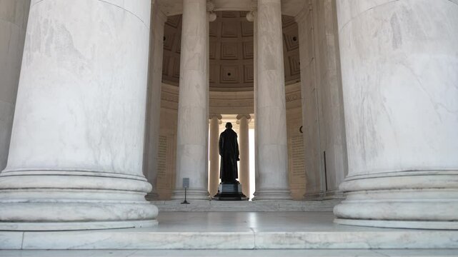 A view of the Jefferson Memorial interior with columns on each side of a statue of Thomas Jefferson. Light streams in from the windows, casting shadows on the marble. - Powered by Adobe
