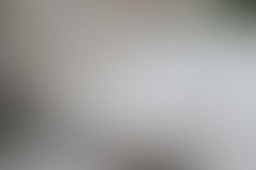 A blurry gray background with a white object in the foreground. Noisy backdrop with grain