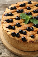 Delicious homemade blueberry pie with mint on wooden table, closeup