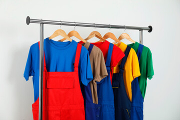 Workers' uniforms on clothing rack near grey wall indoors