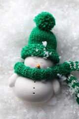 Cute decorative snowman on artificial snow, top view