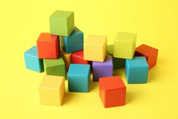 Many wooden colorful cubes on yellow background