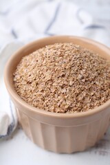 Buckwheat bran in bowl on white table, closeup