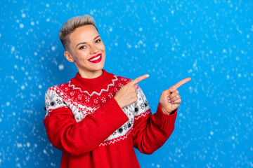 Photo of smiling pretty woman direct fingers copyspace recommend new year sweaters shop cheap prices isolated on bright blue color background