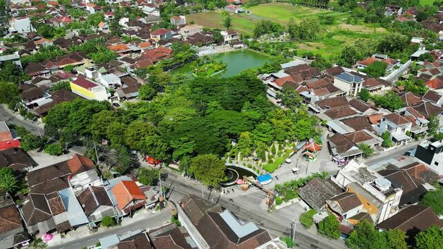 An aerial view of Paku Joyo City Park in Sukoharjo reveals dense trees surrounding a serene lake. The lush greenery and peaceful water create a refreshing, natural escape within the urban landscape.