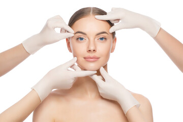Close-up portrait of young female standing with naked skin, face is touched by doctors in gloves,...