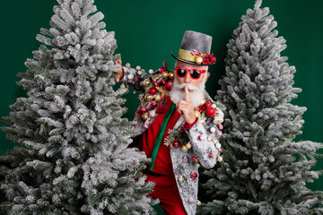 Photo of grandfather decorated outfit show shush gesture snowy christmas tree isolated on dark green color background