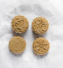 Overhead view of homemade mooncakes, top view of raw mooncakes on white parchment paper, process of making mooncakes for Lunar New Year