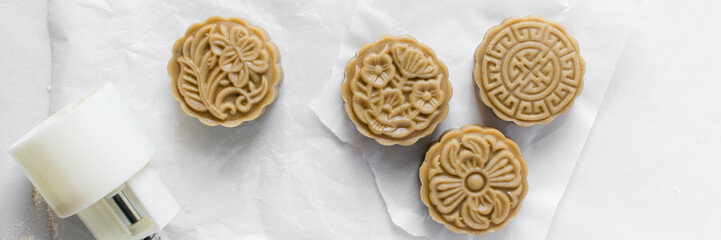 Overhead view of homemade mooncakes, top view of raw mooncakes on white parchment paper, process of making mooncakes for Lunar New Year