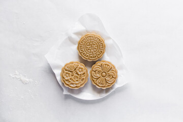Overhead view of homemade mooncakes, top view of raw mooncakes on white parchment paper, process of making mooncakes for Lunar New Year