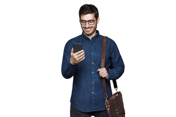 Smiling businessman in glasses and denim shirt standing with phone in hand and bag on shoulder