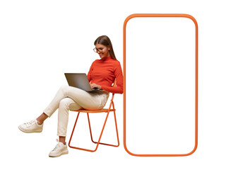 Happy young woman sitting with laptop on chair near blank screen of huge phone, mockup for app