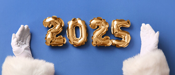 Santa Claus hands with figure 2025 made of balloons on blue background
