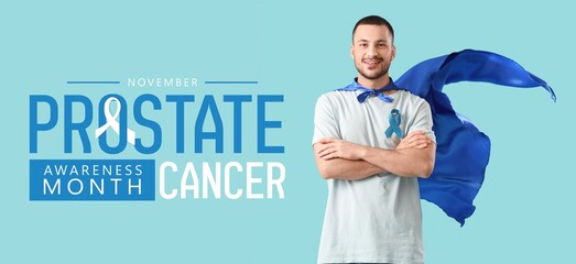 Young man in superhero cape and with blue ribbon on color background. Prostate Cancer Awareness...