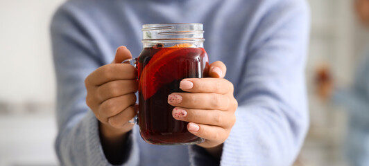 Woman with glass of warm mulled wine in living room at party, closeup