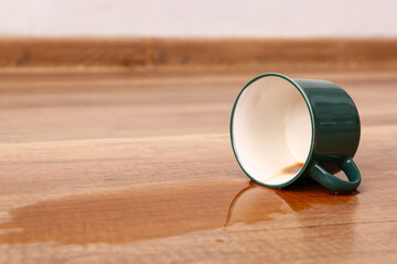 Wooden laminate floor with overturned cup of tea, closeup