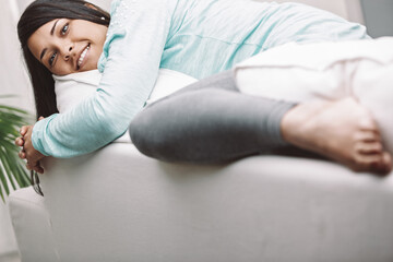 Young woman relaxing on sofa at home feeling happy and in contro